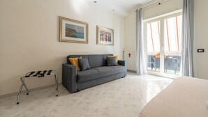 Una sala de estar moderna con un sofá gris, dos cuadros en la pared, una mesita con mantel a rayas blanco y negro, y un ventanal con cortinas.