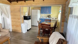 A rustic wooden interior with a dining area, kitchen, and a ceiling fan.