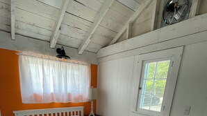 A bedroom with a white bed, a window with a view, and a ceiling fan.