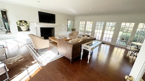 A spacious living area with a fireplace, a large window, and a dining area.