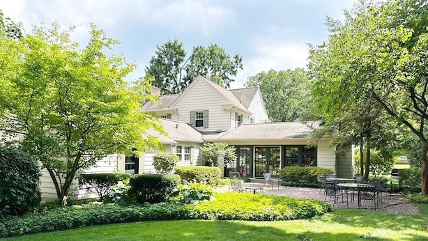 A two-story house with a covered patio and a well-maintained lawn.