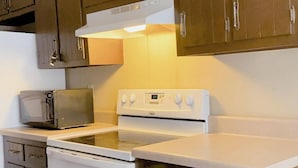 Una cocina con gabinetes marrones, un microondas, un horno y una estufa.