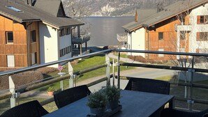 Una terraza con mobiliario exterior, vista a un lago y montañas al fondo.