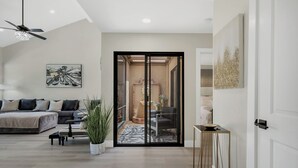 A modern living room with a sofa, coffee table, and a potted plant. - Modern Desert Retreat (Palm Desert)