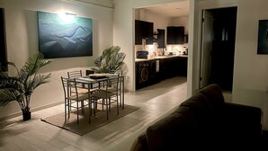 Un soggiorno moderno con zona pranzo, cucina e un corridoio poco illuminato.