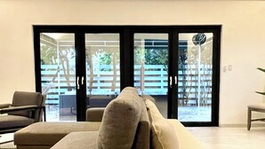Un soggiorno moderno con un divano color beige, un tavolino da caffè e vista su una zona esterna con un pontile in legno e sedie.