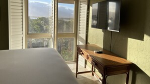 A bedroom with a bed, a desk, and a TV. - Top Floor Beachfront Condo with Ocean view (Kihei)