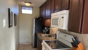 A compact kitchen with a refrigerator, microwave, stove, and sink. - Top Floor Beachfront Condo with Ocean view (Kihei)