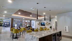 A modern kitchen with a marble island, yellow chairs, and a built-in oven. - King Beds-Walk Score 81 & Parking 3047 (Scottsdale)