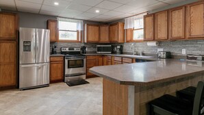 A modern kitchen with wooden cabinets, stainless steel appliances, and a granite countertop. - Creekside Cabin - Watkins Glen, Corning, Finger Lakes with Hot Tub (Corning)