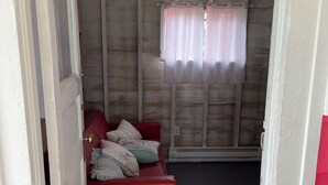 En rød sofa med puder i et rum med trævægge og et vindue med gardiner.