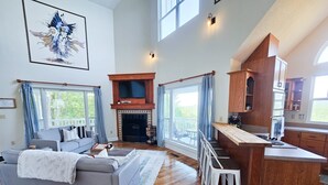 Amplia sala de estar con chimenea, un sofá y una cocina con armarios de madera.