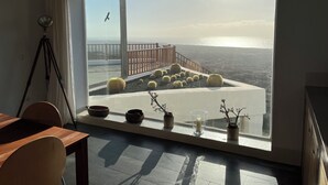 Una stanza con una grande finestra che si affaccia su un balcone con ringhiera e vista sul mare.