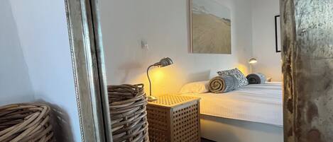 Un dormitorio con una cama, dos mesitas de noche, una lámpara, un cuadro y una alfombra a rayas.