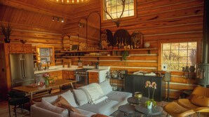 A cozy log cabin interior with a dining area, sofa, and fireplace. - Teanaway Pines: Riverfront Mountain Retreat (Cle Elum)