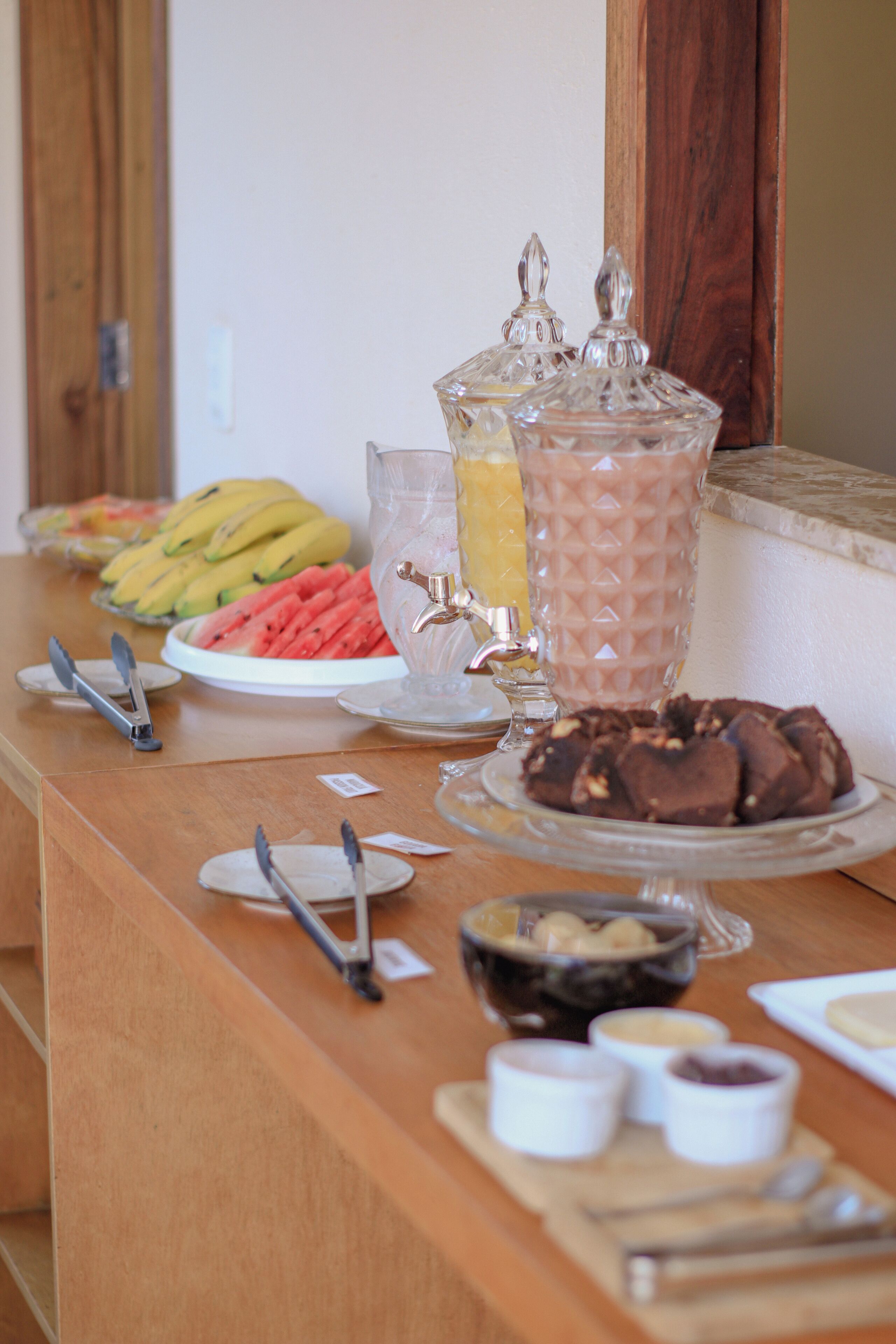 A buffet table with various food items including fruits, a blender, and condiments.