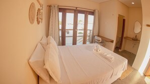 Habitació d'hotel amb llit, escriptori, bany i balcó.
