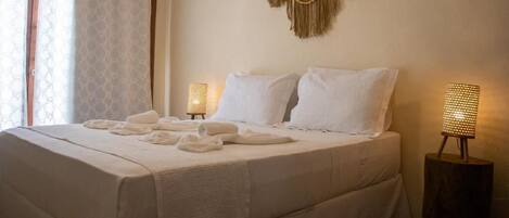 A hotel room with a large bed, two bedside lamps, and a decorative wall hanging.