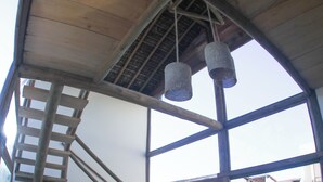 Un interior modern amb una escala de fusta, dues cadires, una taula petita i un llum penjant.