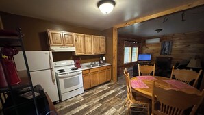 A kitchen with wooden cabinets, a stove, and a dining table with chairs.