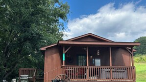 A wooden cabin with a porch, a large wheel, and a sign indicating hot tub safety rules.