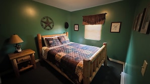 A bedroom with a wooden bed, a nightstand, a lamp, a star decoration, and a window with blinds.