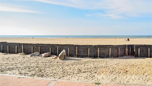 A beach with a wooden fence and rocks in the foreground, and a few people in the distance. - Cozy home in Neuilly le Vendin with WiFi (Neuilly le Vendin)
