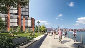 A modern building with large windows and a brick facade, adjacent to a waterfront promenade with benches and cyclists. - Gorgeous apt for Labor Day weekend.  View of Manhattan at Greenpoint 



 (Brooklyn)