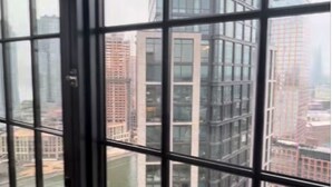 A view through a window with a grid pattern, overlooking a cityscape with tall buildings and a river. - Gorgeous apt for Labor Day weekend.  View of Manhattan at Greenpoint 



 (Brooklyn)