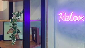 Et værelse med et neon skilt der siger 'Relax', træhylder og et indrammet billede.