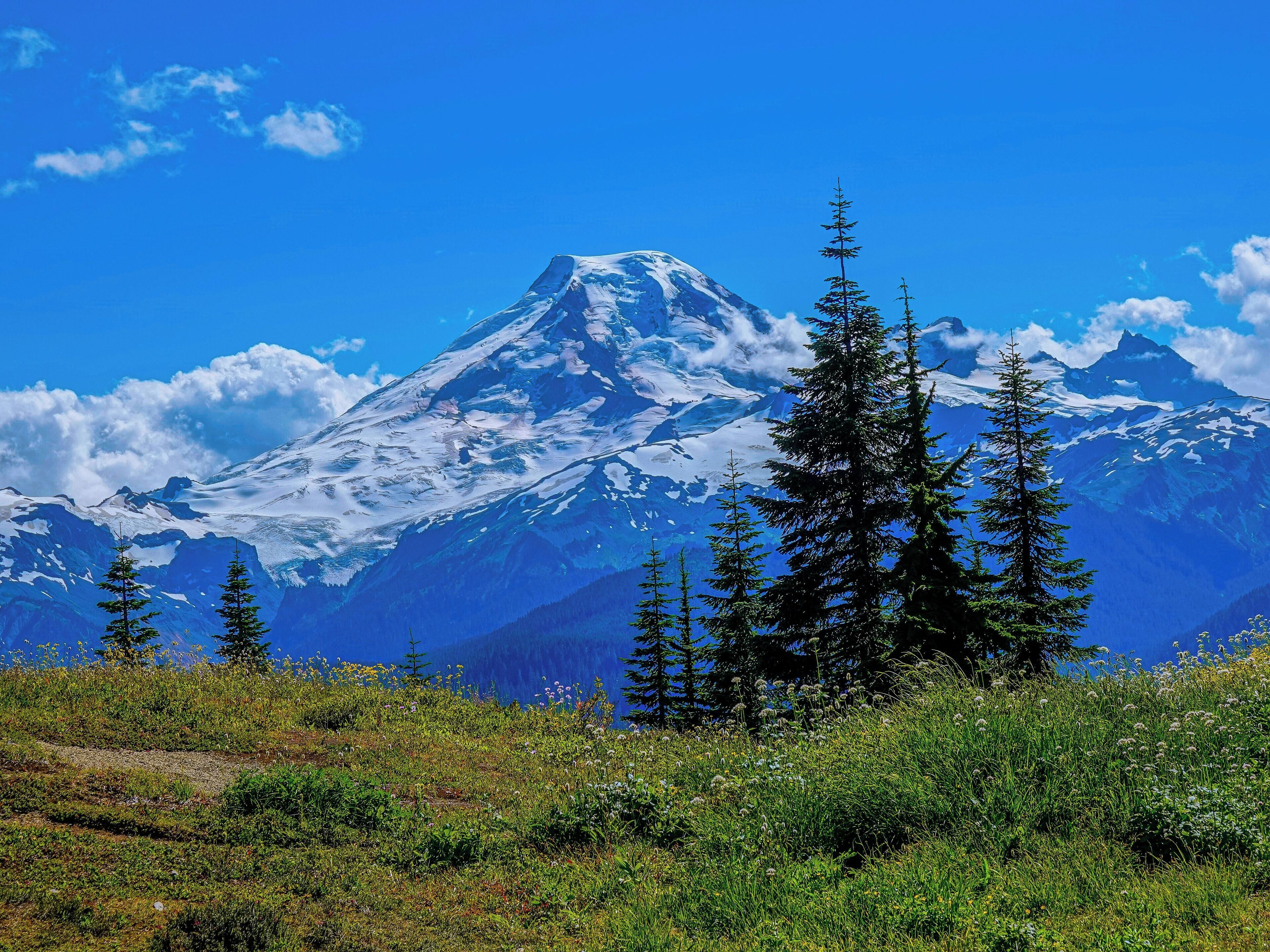 Une montagne aux sommets enneigés, sous un ciel bleu azur.