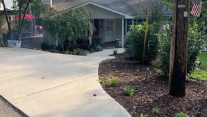 A residential driveway leading to a house with a front porch, surrounded by trees and a small garden area. - 3 LITTLE BEARS DEN AT BEAR PAW
GREAT FAMILY VACATION HOME. EVERYTHING YOU NEED (Murphy)