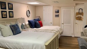 A bedroom with two beds, a wooden floor, a white door, and a wall-mounted lamp. - 3 LITTLE BEARS DEN AT BEAR PAW
GREAT FAMILY VACATION HOME. EVERYTHING YOU NEED (Murphy)