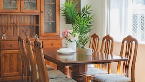 Ein Esstisch mit Stühlen, einer floralen Tischdekoration und einem Holzschrank mit Glastüren.