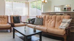 Ein Wohnzimmer mit einem beigen Ledersofa, zwei passende Sessel, einem dunklen Couchtisch und einer Stehlampe.