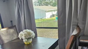 A compact dining area with a table, chairs, and a window with curtains. - Cozy RV off the Withlacoochee River (Dunnellon)