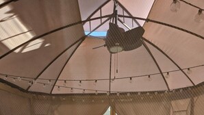 A room with a large umbrella canopy, a sofa, a coffee table, and a view of the outdoors. - Cozy RV off the Withlacoochee River (Dunnellon)