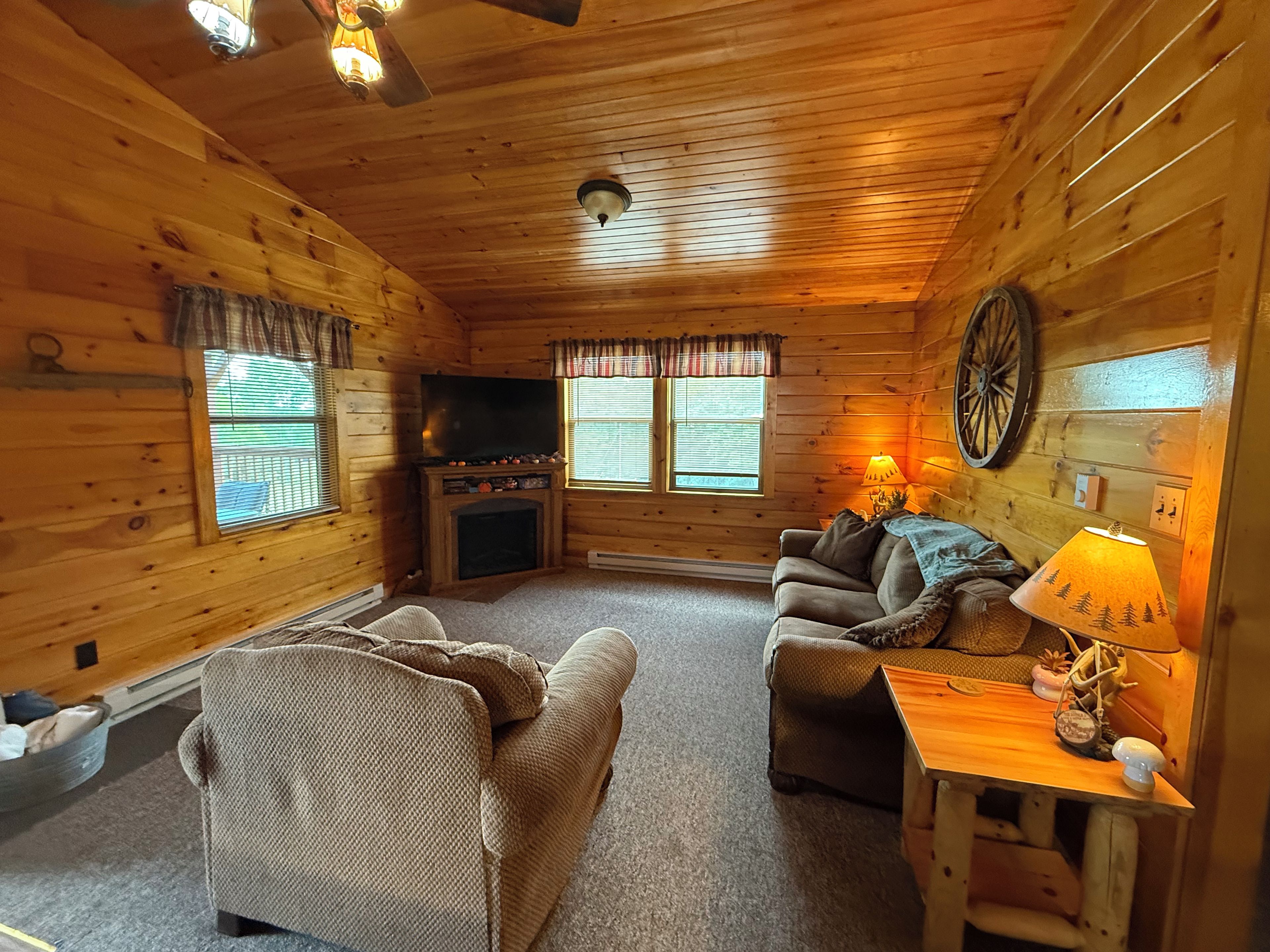 Ein gemütliches Ferienhäuschen mit Kamin, Fernseher, Sofa und Lampe.