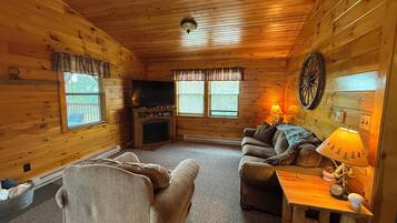 Ein gemütliches Ferienhäuschen mit Kamin, Fernseher, Sofa und Lampe.