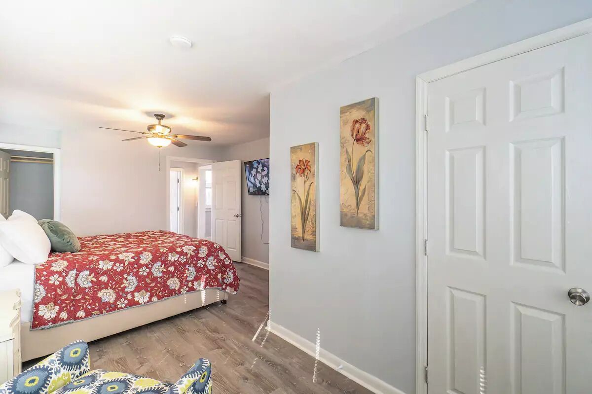 A bedroom with a bed, a ceiling fan, and a door.