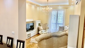 A living room with a sofa, TV, chandelier, and a dining area with chairs and a table. - Belgrade heart of historical center (Belgrade)
