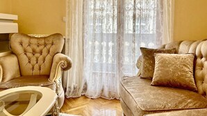 A living room with a tufted armchair, a sofa with patterned cushions, and a glass coffee table. - Belgrade heart of historical center (Belgrade)