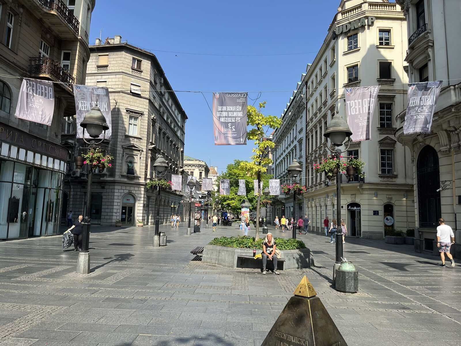 Ein weitläufiger öffentlicher Platz mit historischen Gebäuden, Wimpeln und einem zentralen Denkmal.