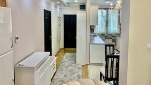 A modern kitchen with white cabinets, a built-in oven, and a countertop. There is a dining area with a table and chairs, and a hallway leading to a door. - Belgrade heart of historical center (Belgrade)