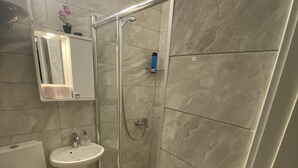 A modern bathroom with a glass-enclosed shower, a pedestal sink, and a toilet. - APARTMENT PERLA (Pristina)