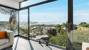 A modern room with large floor-to-ceiling windows, a sofa, and a view of a coastal landscape. - Stunning Ocean Views; 2 Pools;10 min walk to beach (Sayulita)