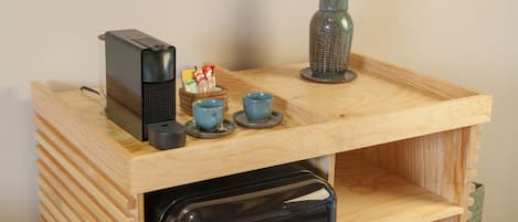 Una kitchenette compacta con cafetera, un refrigerador pequeño y una encimera de madera.