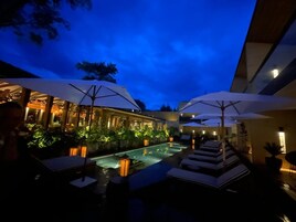 Una piscina al aire libre, sombrillas, sillones reclinables de piscina