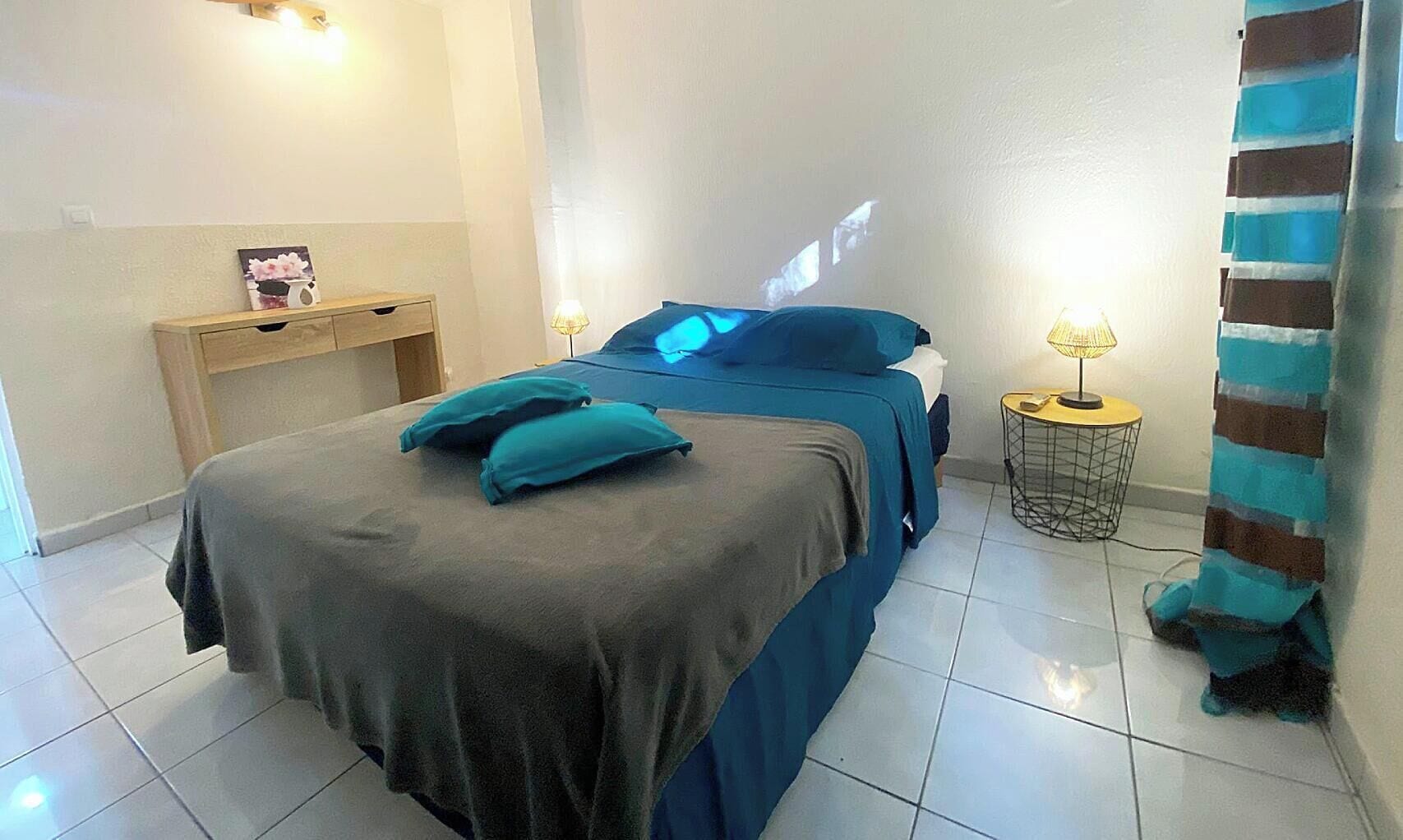 Een slaapkamer met een bed, nachtkastjes en een projectiescherm.