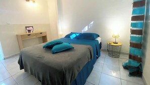 A bedroom with a bed, bedside tables, and a projector screen. - Vue mer Imprenable ! F2 2/4 Pers, Jacuzzi Privatif et Piscine Privée (Les Trois-Îlets)
